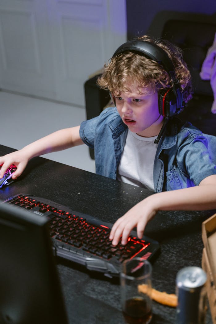 Young boy wearing headphones focused on computer gaming.